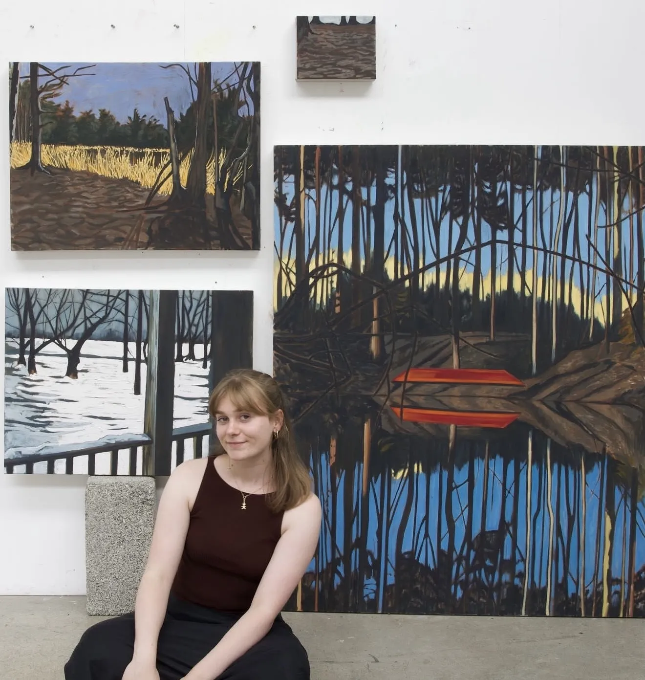 Georgia Dalzell in the studio, in front of landscape paintings